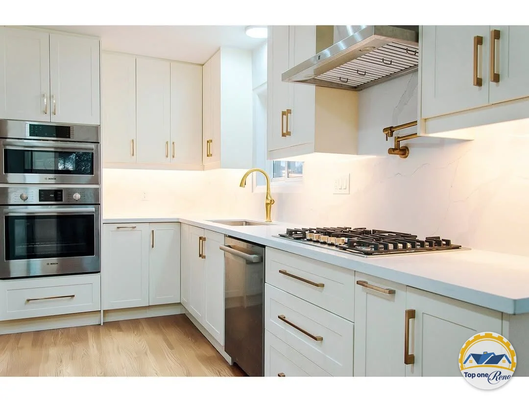 Completed white kitchen renovation by Top One Reno, featuring brass fixtures and stainless steel appliances